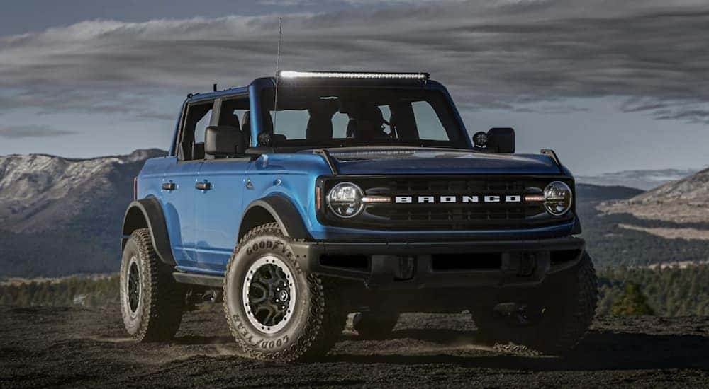 A blue 2021 Ford Bronco is angled right parked in a field after looking at a used Ford Bronco dealer.