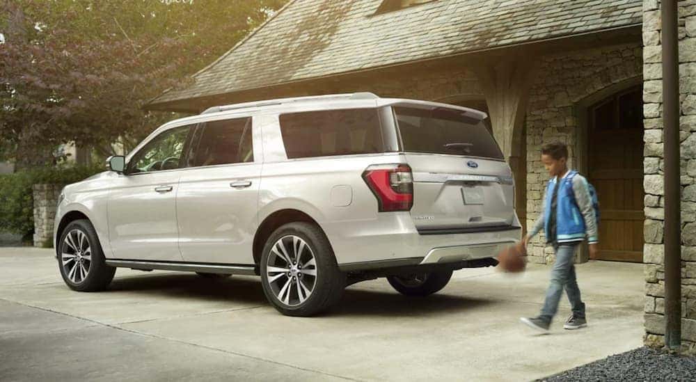 A white 2021 Ford Expedition is shown from the side parked in front of a modern house.