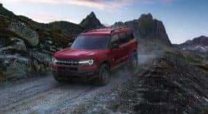 A red 2022 Ford Bronco Sport Big Bend is shown driving on a dirt road.