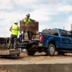 A blue Ford F-250 Super Duty is shown from the rear at an angle while being loaded on a job site after the owner searched 'used Ford diesel trucks'.