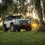 A green 2022 Ford Bronco Everglades is shown from the front in a forest clearing after leaving one of the Albany car dealers.