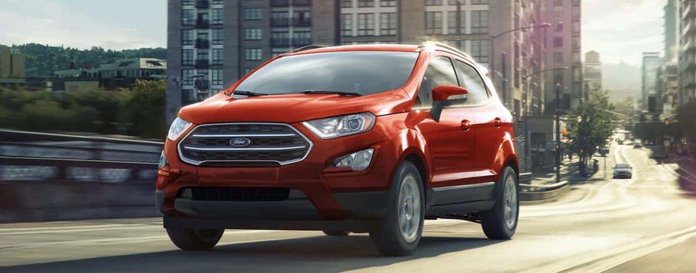 A red 2022 Ford EcoSport is shown from the front driving on an open road during a 2022 Ford EcoSport vs 2022 Chevy Trax comparison.