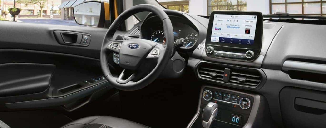 The black interior of a 2022 Ford EcoSport shows the steering wheel and infotainment screen.