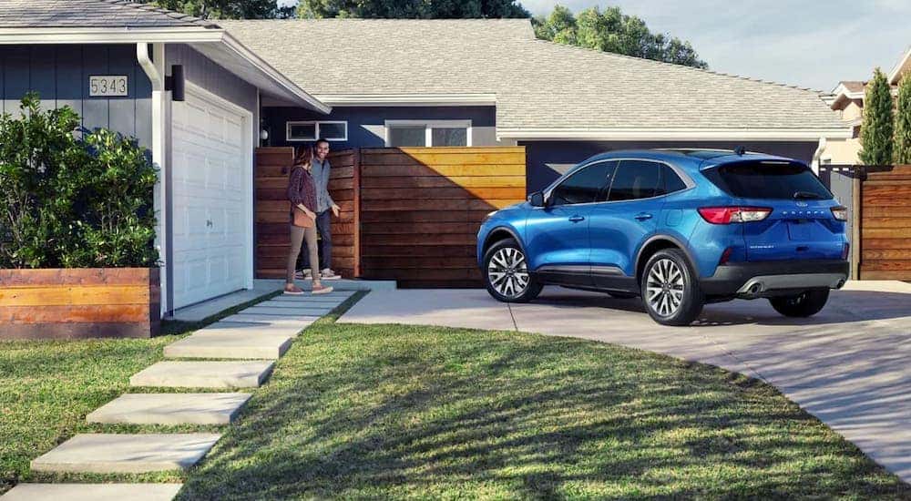 A blue 2020 Ford Escape is shown from the rear while parked in front of a house.