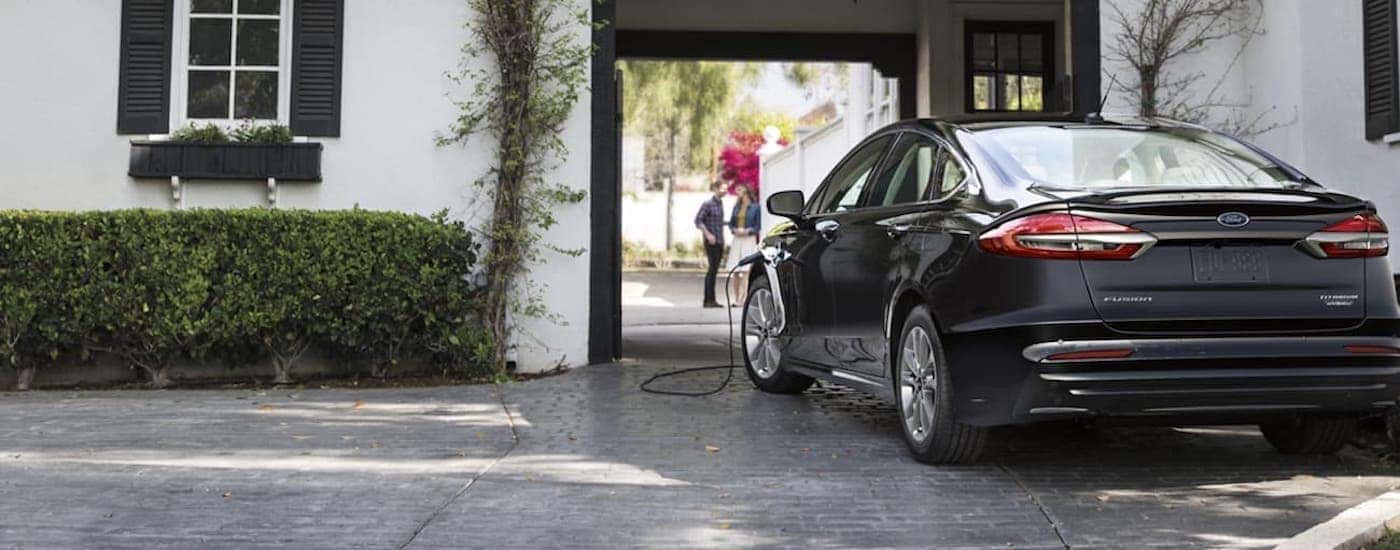 A black 2020 Ford Fusion is shown from the rear parked in front of a house.