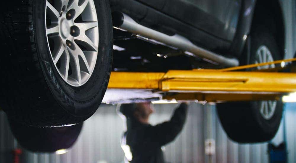 A mechanic is shown inspecting a car on a lift.