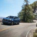 One of the most popular Ford SUVs, a blue 2022 Ford Edge, is shown driving on a mountain road.