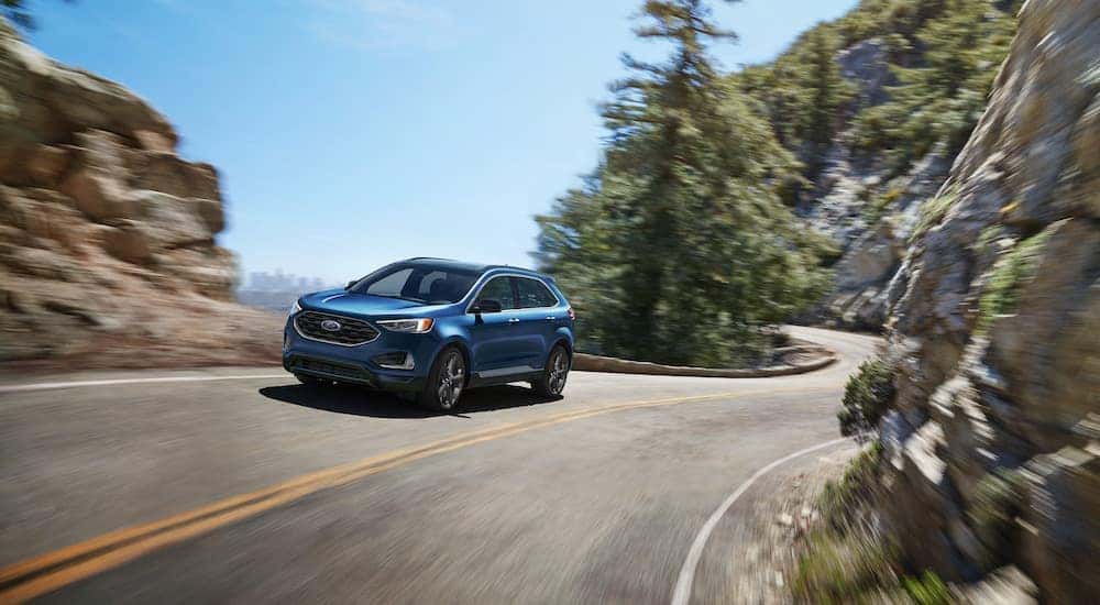 One of the most popular Ford SUVs, a blue 2022 Ford Edge, is shown driving on a mountain road.