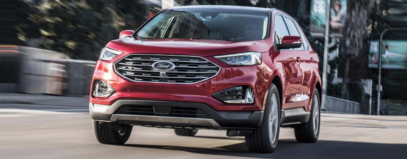 A red 2019 Ford Edge Titanium is shown driving on a city street.