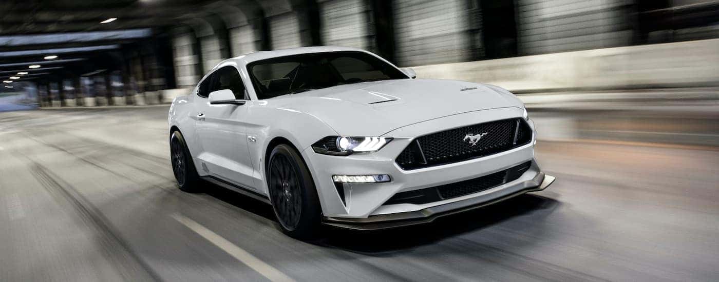 A popular Certified Pre-Owned Ford, a white 2020 Ford Mustang GT, is shown driving through a tunnel.