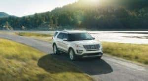 A white 2016 Ford Explorer is shown driving past a river after visiting a Ford Explorer dealership.