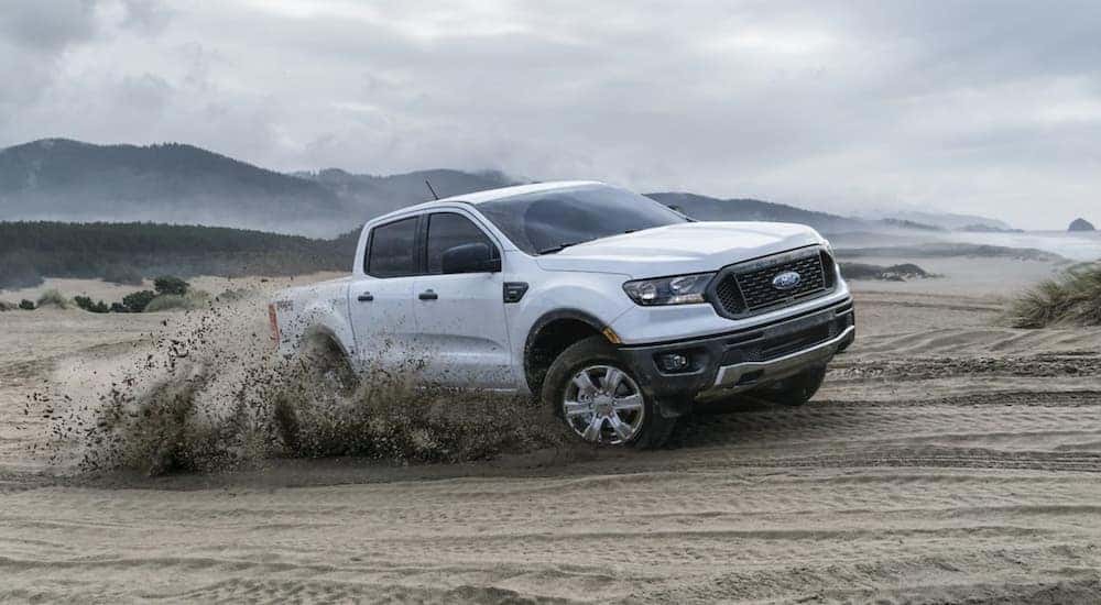 A white 2019 Ford Ranger is shown driving on a sandy beach.