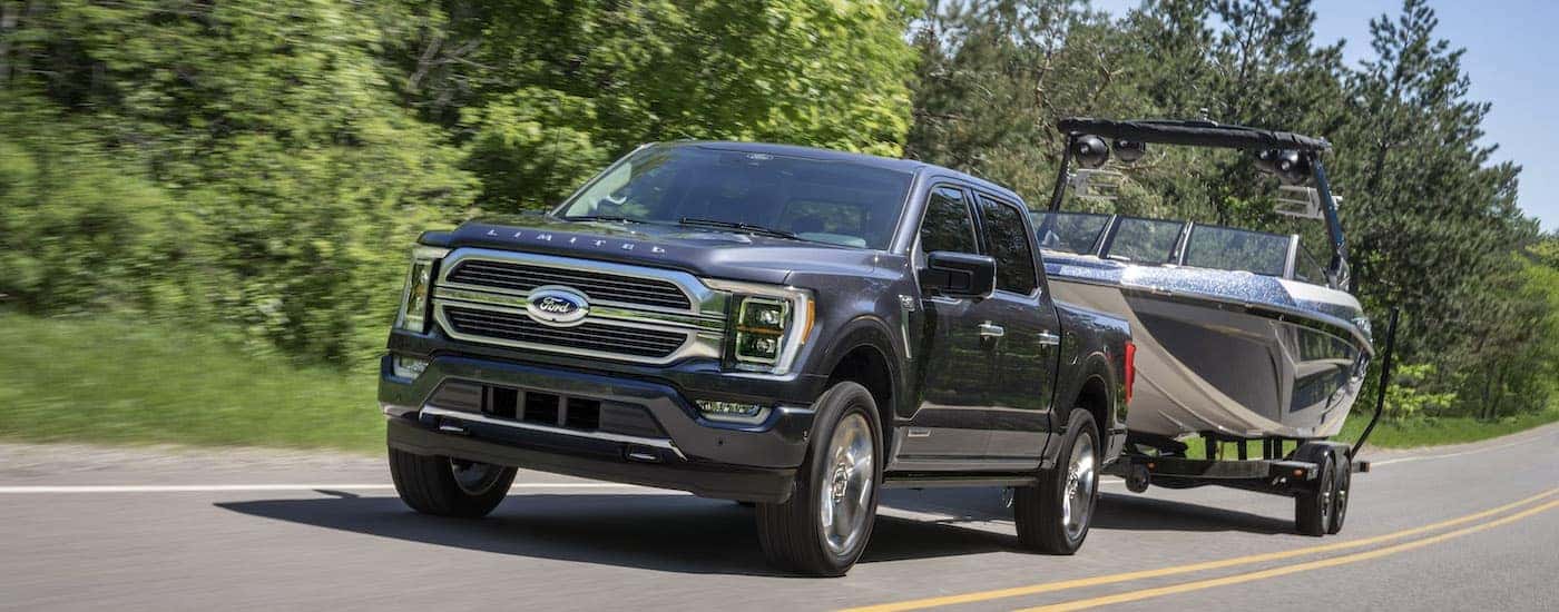 A grey 2022 F-150 is shown from the front while towing a boat after leaving an Albany F-150 dealer.