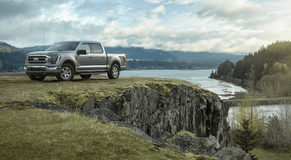 A grey 2022 Ford F-150 is shown parked on a cliff overlooking a lake.