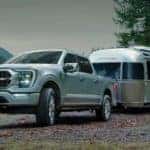 A silver 2022 Ford F-150 is shown towing an Airstream near a lake after leaving an Albany F-150 dealer.