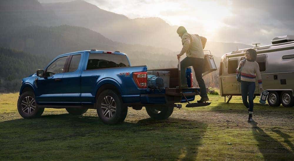 A blue 2022 Ford F-150 is shown being loading a at a campsite.