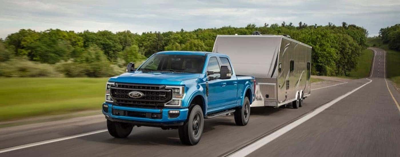 A blue 2020 Ford F-250 Tremor is shown from the front at an angle while towing a camper.