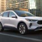 A white 2023 Ford Escape is shown on a city street after leaving an Albany Escape dealer.