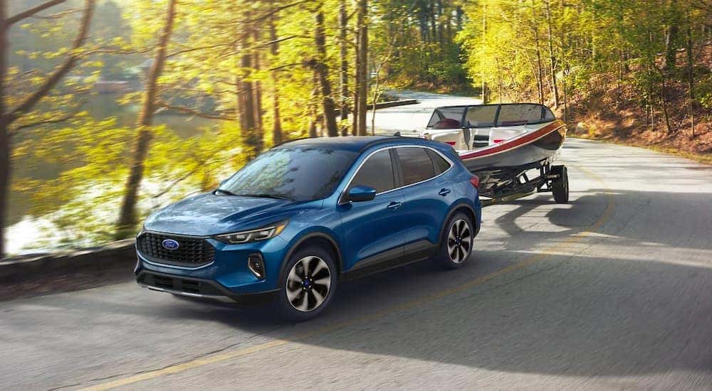 A blue 2023 Ford Escape ST-Line Elite is shown towing a boat.