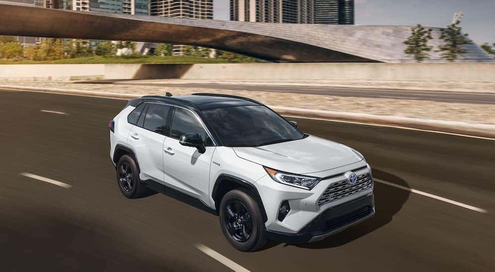 A white 2021 Toyota RAV4 is shown from the front driving on an open road.