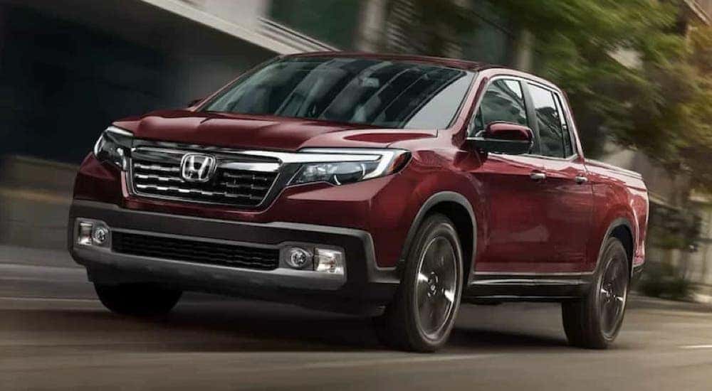 A red 2020 Honda Ridgeline RTL-E is shown driving on a city street.