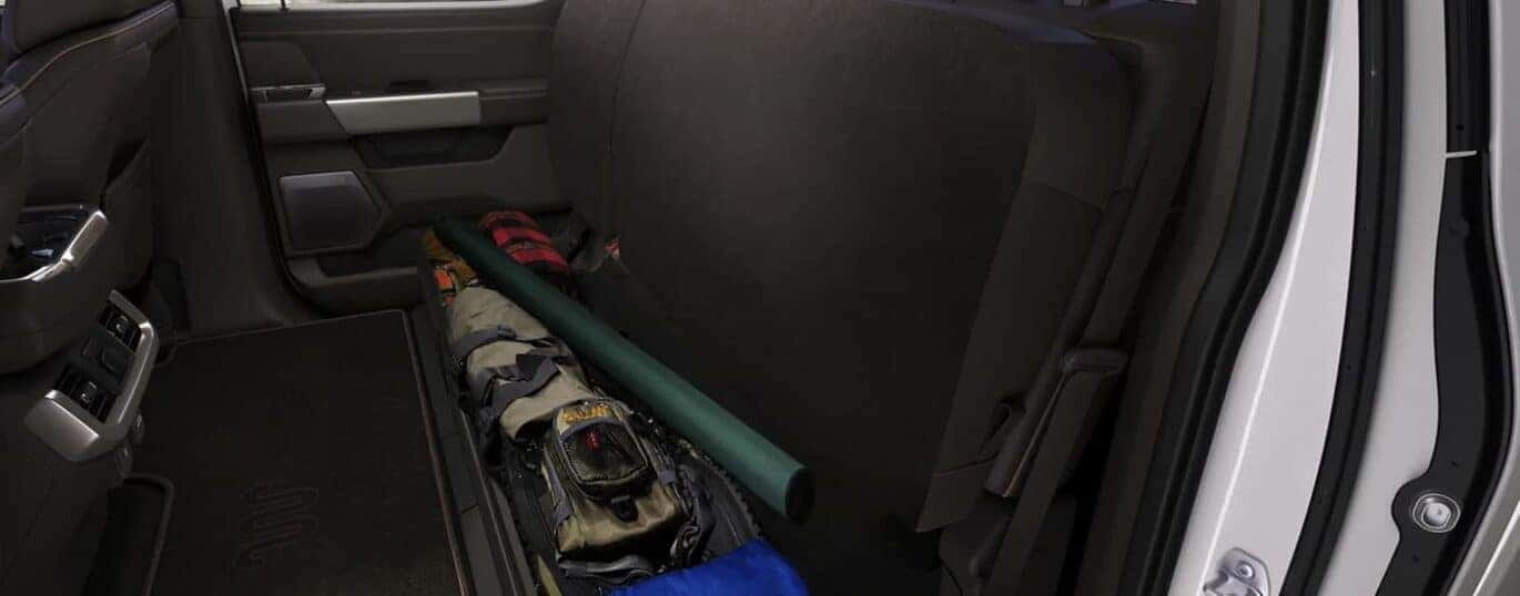 The cab under-seat storage in a white 2023 Ford F-150 is shown.