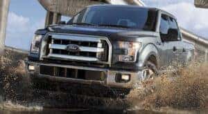 A grey 2017 Ford F-150 XLT is shown from the front at an angle while driving through mud.