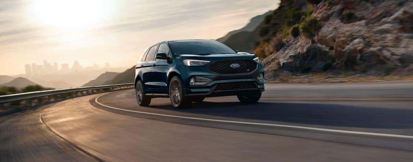 A dark blue 2023 Ford Edge ST is shown rounding a corner.