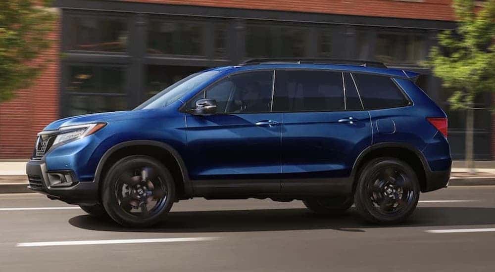 A blue 2022 Honda Passport is shown from the side on a city street after leaving a dealer that handles Troy used SUV sales.