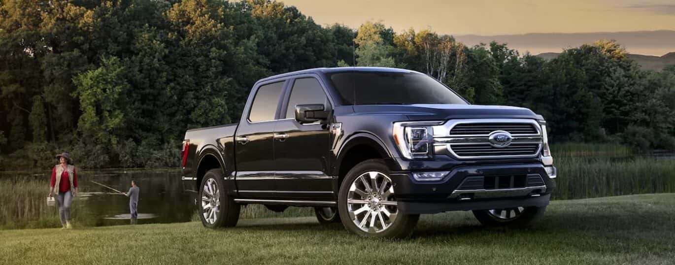 A black 2023 Ford F-150 is shown parked near a pond during a 2023 Ford F-150 vs 2023 GMC Sierra 1500 comparison.