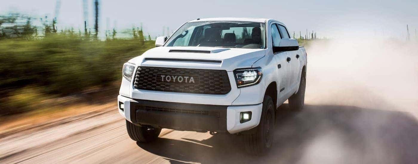 A white 2019 Toyota Tundra driving on a dusty dirt road.