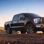 A black 2021 Ford F-150 is shown parked on a dirt hill after visiting a Saratoga, NY used Ford dealer.