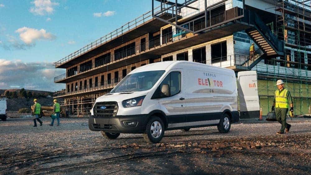 A white 2021 Ford Transit is shown parked on a construction site.