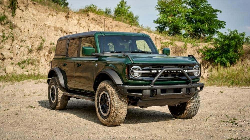 A green 2022 Ford Bronco is shown parked outdoors on a dirt path.
