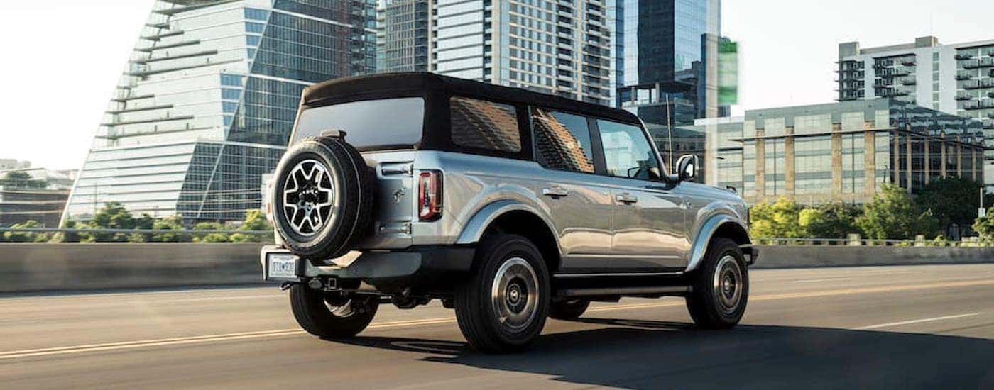 A silver 2021 Ford Bronco Outer Banks is shown from the rear at an angle after leaving a used Ford SUV dealer near Amsterdam.