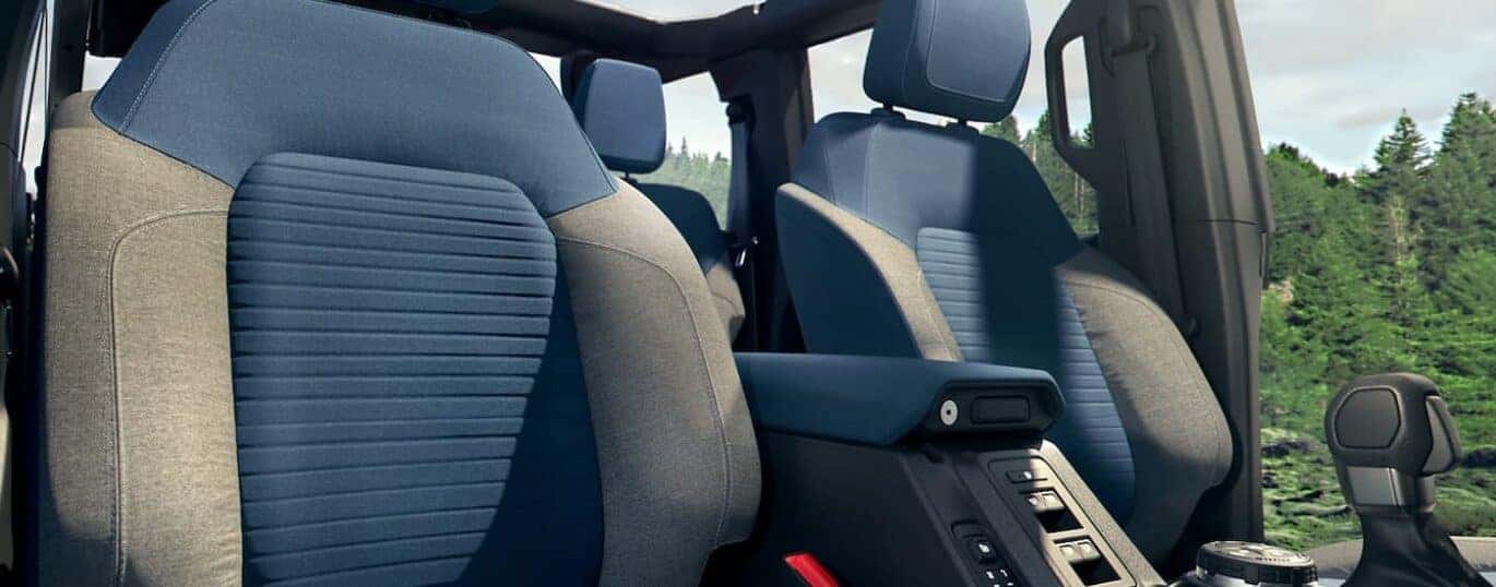 The grey and blue interior of a 2023 Ford Bronco Outer Banks shows the front seating and center console.