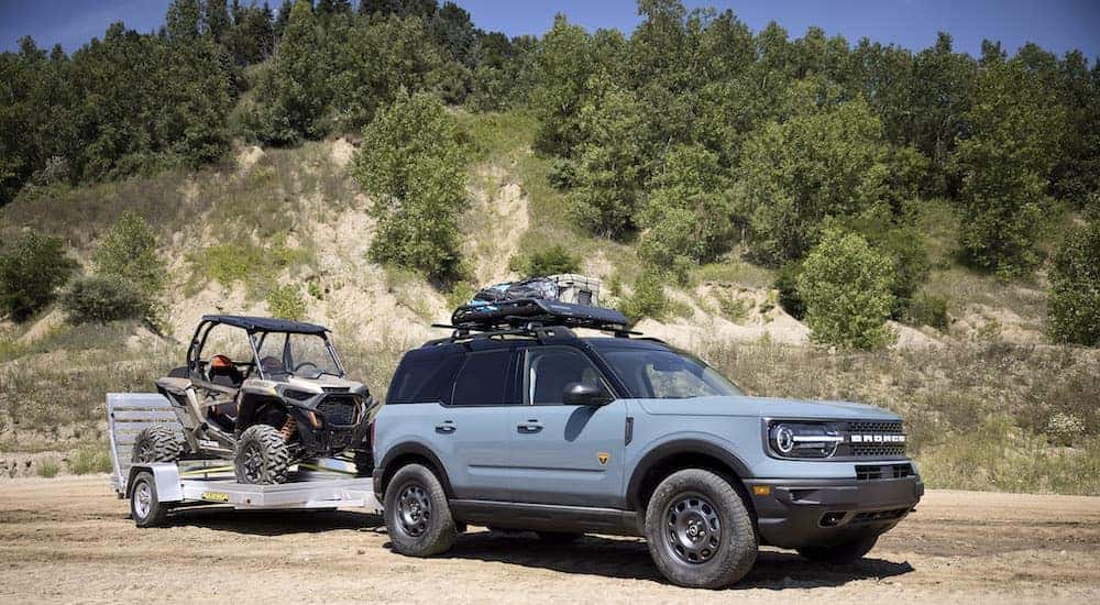 A blue 2021 Ford Bronco Sport is shown from the front while towing a UTV.