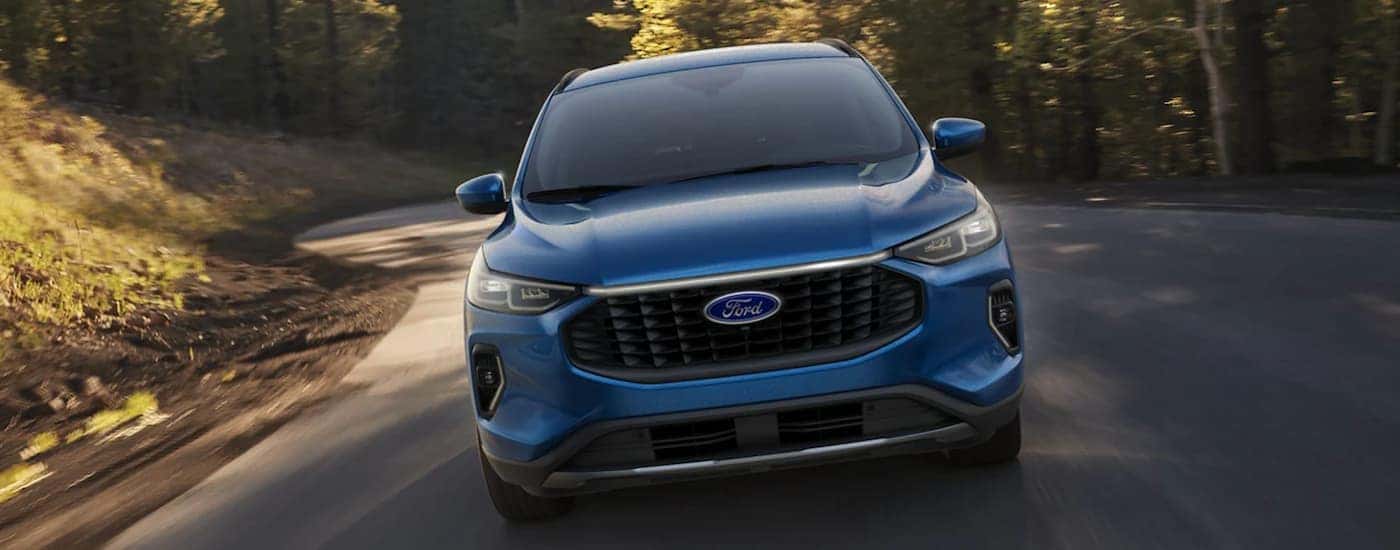 A blue 2023 Ford Escape is shown from the front driving on an open road.