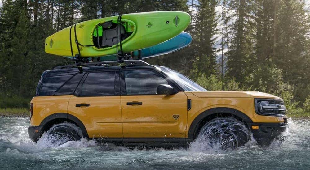 A yellow 2021 Ford Bronco Sport is shown from the side while crossing a river.