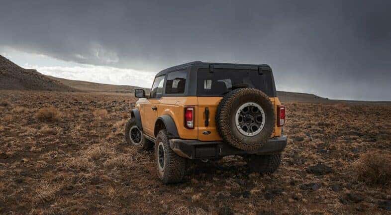 An orange 2022 Ford Bronco is shown from the rear in an open field.