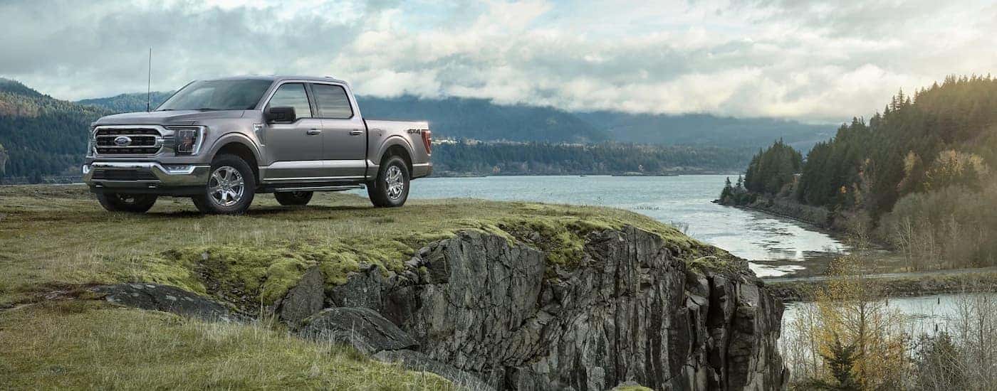 A silver 2023 Ford F-150 XLT is shown parked in front of a lake.