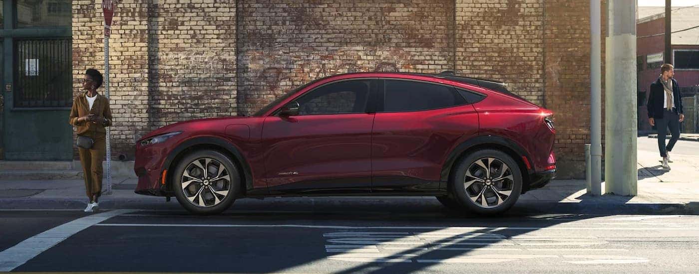 A red 2023 Ford Mustang Mach-E is shown from the side parked on a side street after leaving a Ford dealership.