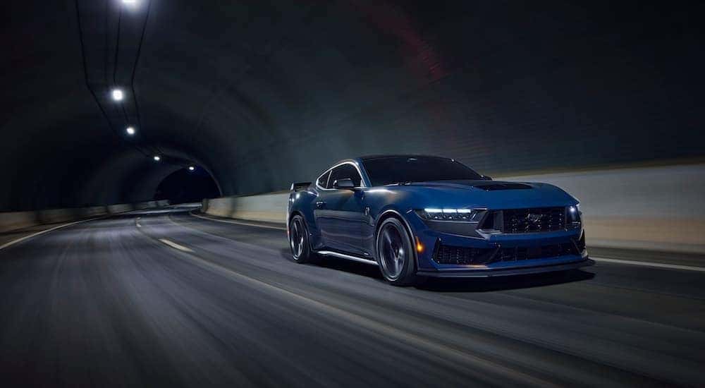 A blue 2024 Ford Mustang Dark Horse is shown from the front at an angle after leaving a Ford dealership.