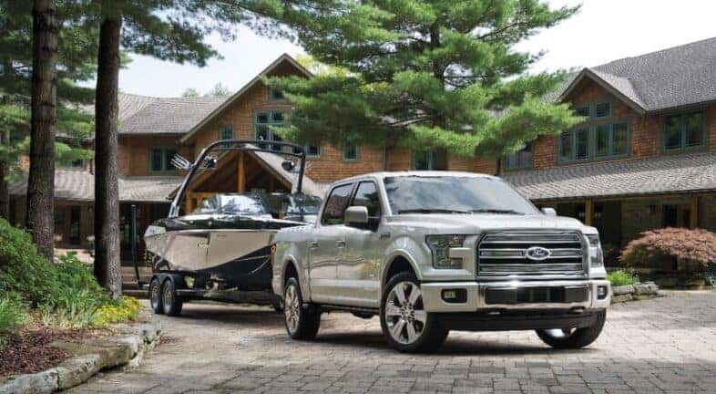 A white 2016 Ford F-150 Limited is shown parked in a driveway with a boat trailer.