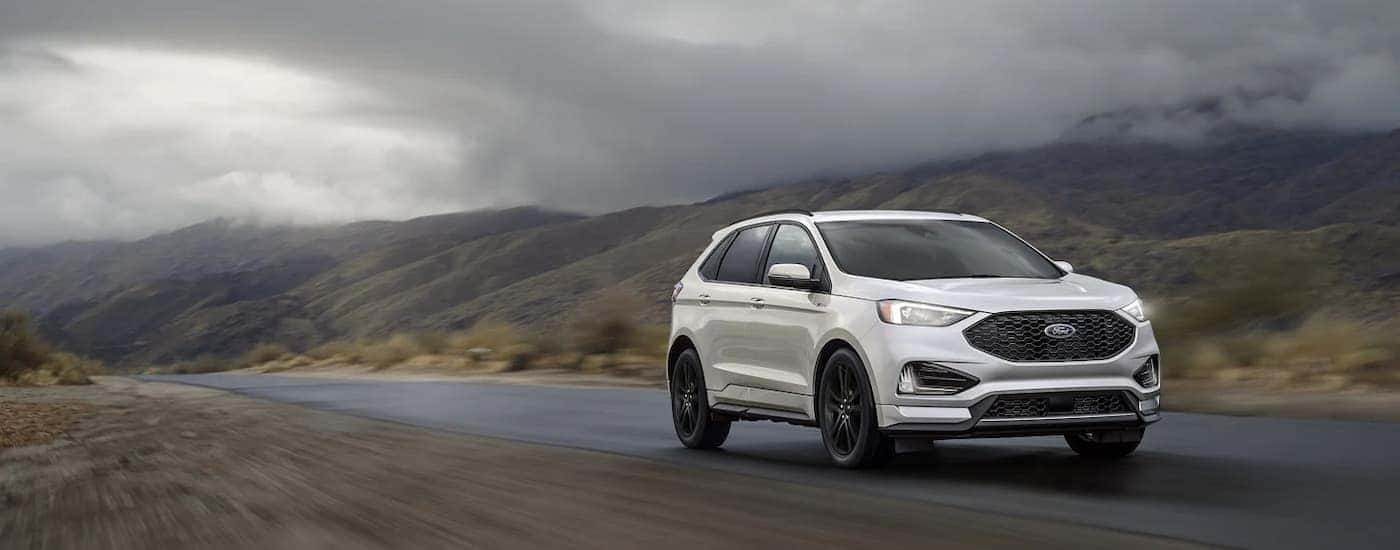 A white 2022 Ford Edge is shown driving on an open road after leaving a used car dealer near Bethlehem.