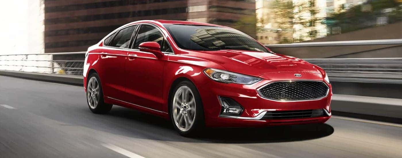 A red 2020 Ford Fusion is shown driving on a city freeway.