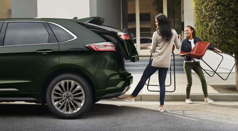 People are shown loading chairs into the trunk of a green 2023 Ford Edge.