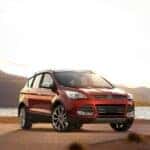 A red 2016 Ford Escape is shown in front of a lake.