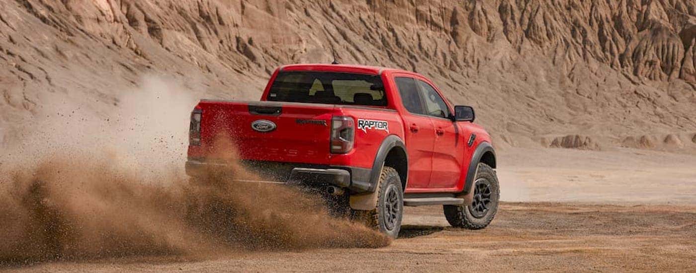 A red 2024 Ford Ranger Raptor is shown from the rear at an angle.