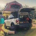 A family is shown setting up camp around a white 2024 Ford Bronco Sport Badlands after visiting a Ford dealership near Cohoes.